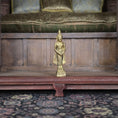 Load image into Gallery viewer, Gold statue on a wooden platform with a patterned rug below