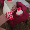 Load image into Gallery viewer, Close-up of a Dollhouse miniature red and cream hand knitted sweater sleeve draped over an armchair