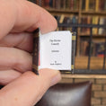 Load image into Gallery viewer, Hand holding a miniature book titled 'The Divine Comedy' with a blurred bookshelf in the background.