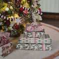 Load image into Gallery viewer, Stack of Christmas-themed gift boxes in front of a decorated tree.