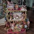 Load image into Gallery viewer, Decorative Christmas scene with figurines and ornaments on a wooden surface.