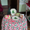 Load image into Gallery viewer, Christmas-themed table setting with decorative cards and a small tree on a floral tablecloth.