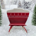 Load image into Gallery viewer, Red sleigh with white seats in a snowy landscape, back view