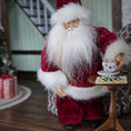 Load image into Gallery viewer, Santa Claus dollhouse doll holding a cup and saucer with a Christmas tree and presents in the background