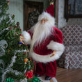 Load image into Gallery viewer, Santa Claus dollhouse doll decorating a Christmas tree in a cozy room.