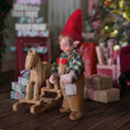 Load image into Gallery viewer, Clay elf character with a wooden horse in a festive setting with presents and a Christmas tree.