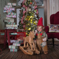 Load image into Gallery viewer, Clay elf character with a wooden horse in a festive room with Christmas tree and presents.