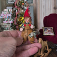 Load image into Gallery viewer, Hand holding a Clay elf character doll in a festive setting with Christmas decorations.
