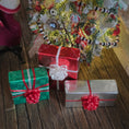 Load image into Gallery viewer, Decorative Christmas scene with wrapped gifts and a tree in the background.