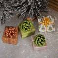 Load image into Gallery viewer, Gift boxes with decorative bows under a frosted Christmas tree on a textured surface.