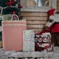 Load image into Gallery viewer, Christmas-themed gift boxes with a decorative bag and Santa Claus figure in the background.