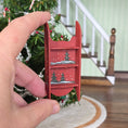 Load image into Gallery viewer, Hand holding a small red sled with Christmas tree design in front of a decorated Christmas tree.