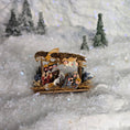 Load image into Gallery viewer, Miniature nativity scene set against a snowy landscape with trees.