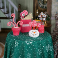 Load image into Gallery viewer, Decorative Christmas items on a table with a green tablecloth featuring snowflake patterns.