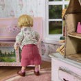 Load image into Gallery viewer, Back of Catherine Muniere Doll in a floral shirt and pink skirt standing in a dollhouse room with floral wallpaper.