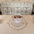 Load image into Gallery viewer, Miniature pastry in a dome on a decorative plate with a floral cabinet in the background
