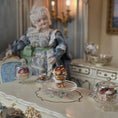 Load image into Gallery viewer, Vintage doll in a decorative setting with a table of pastries and tea cups.