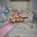 Load image into Gallery viewer, Miniature board of pastries held on a finger with a blurred background