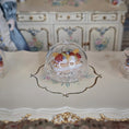 Load image into Gallery viewer, Decorative cake with a glass dome on an ornate table