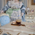 Load image into Gallery viewer, Glass of dark liquid on a decorative table with a person in the background