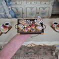 Load image into Gallery viewer, Miniature tray with pastries held by a finger in front of a decorative background