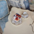 Load image into Gallery viewer, Small tart with berries on a decorative stand next to a teacup on a patterned surface.