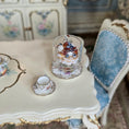 Load image into Gallery viewer, Miniature pastry on a decorative table with a blue floral chair in the background