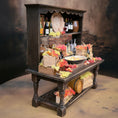 Load image into Gallery viewer, Decorative setup with a dark wooden cabinet and table, featuring flowers and bottles, against a rustic background.