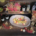 Load image into Gallery viewer, Wine bottles, fruit, and decorative items on a wooden surface