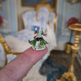 Load image into Gallery viewer, Miniature figurine held balanced on top of a finger with a decorative interior background