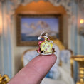 Load image into Gallery viewer, Small decorative figurine held atop a finger with an ornate room in the background