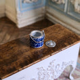 Load image into Gallery viewer, Blue and white ceramic container with silver lid on a wooden surface
