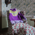 Load image into Gallery viewer, Knitted purple sweater (Dollhouse miniature) on a patterned chair with floral wallpaper in the background