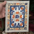 Load image into Gallery viewer, Hand holding a cross-stitched miniature rug with intricate patterns