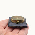 Load image into Gallery viewer, Backside of block with brass component held in a hand against a white background