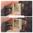 Load image into Gallery viewer, Miniature book held between fingers with a blurred bookshelf background