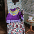 Load image into Gallery viewer, Patterned chair with a purple knitted sweater draped over it, next to a small wooden table with a teacup.