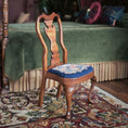 Load image into Gallery viewer, Wooden chair with a petit point cushion on a rug in a room with a green bed in background.