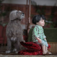 Load image into Gallery viewer, Miniature Chinese dollhouse character doll by Svetlana Blasing in a green outfit sitting on a red cushion next to a dog figurine.