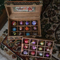 Load image into Gallery viewer, Wooden box with colorful glass ornaments on a patterned rug