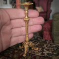Load image into Gallery viewer, Gold candlestand held in a hand with a blurred indoor background