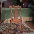 Load image into Gallery viewer, Wooden chair with intricately carved wood backrest on a patterned rug in a room with green bed and colorful decor.