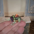 Load image into Gallery viewer, Miniature fruit and berry centerpiece arrangement held in a hand with a blurred background
