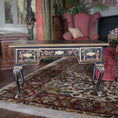 Load image into Gallery viewer, Hand painted decorative Chinoiserie desk with floral patterns on a patterned rug in a room with a pink chair and fireplace.