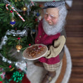 Load image into Gallery viewer, Old Christmas Elf doll with a beard holding cookies in front of a decorated Christmas tree.