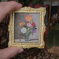 Load image into Gallery viewer, Decorative dollhouse gold frame with a floral oil painting on a fabric background by Fatima Dona
