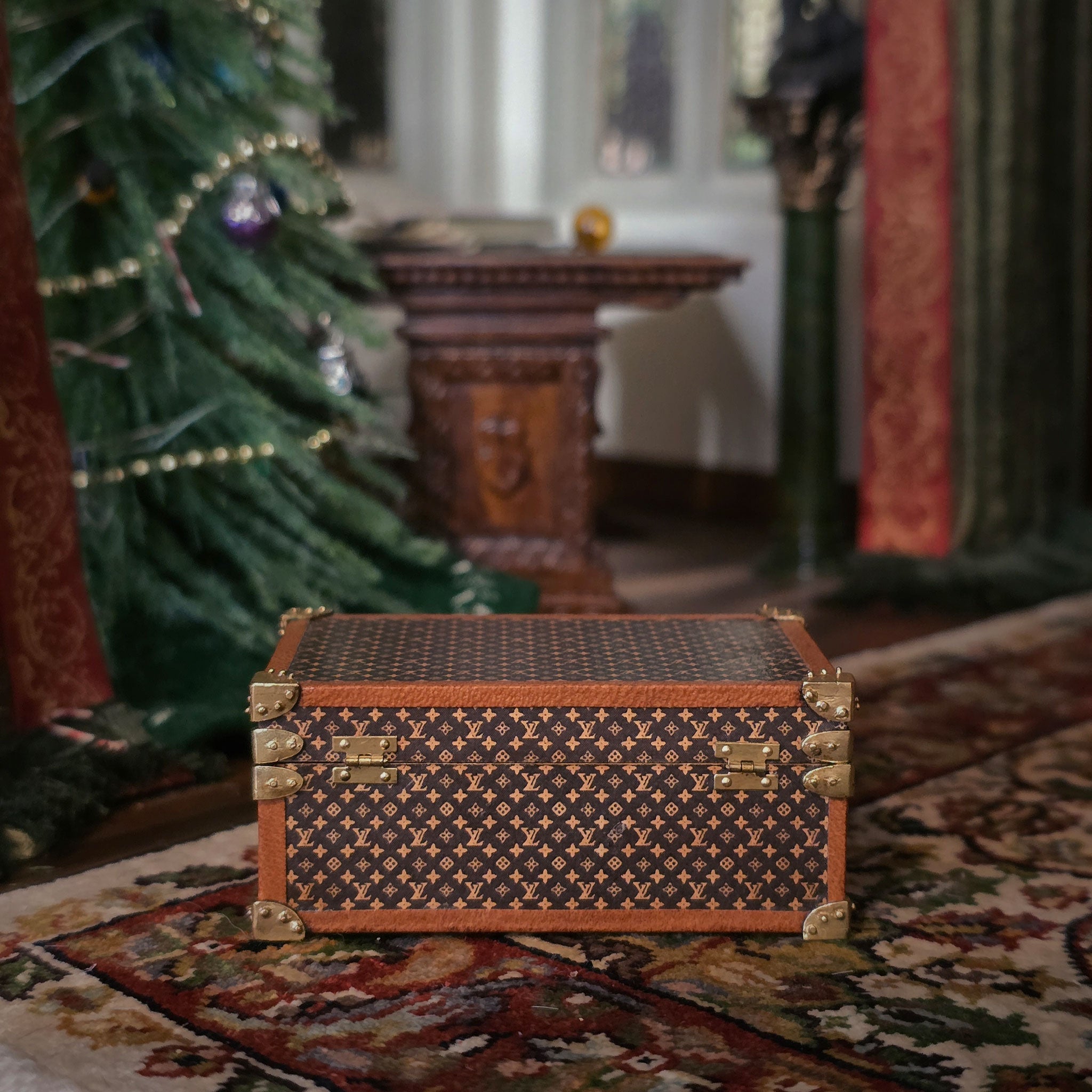 Decorative wood and brass chest on a patterned rug with a Christmas tree in the background