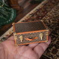Load image into Gallery viewer, Miniature patterned suitcase held in a hand on a textured surface
