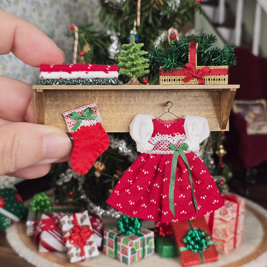 Dollhouse Miniature red dress with green details and a Christmas-themed wall shelf display.
