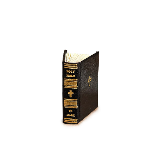 Black leather-bound book with gold embossed text and cross on a white background